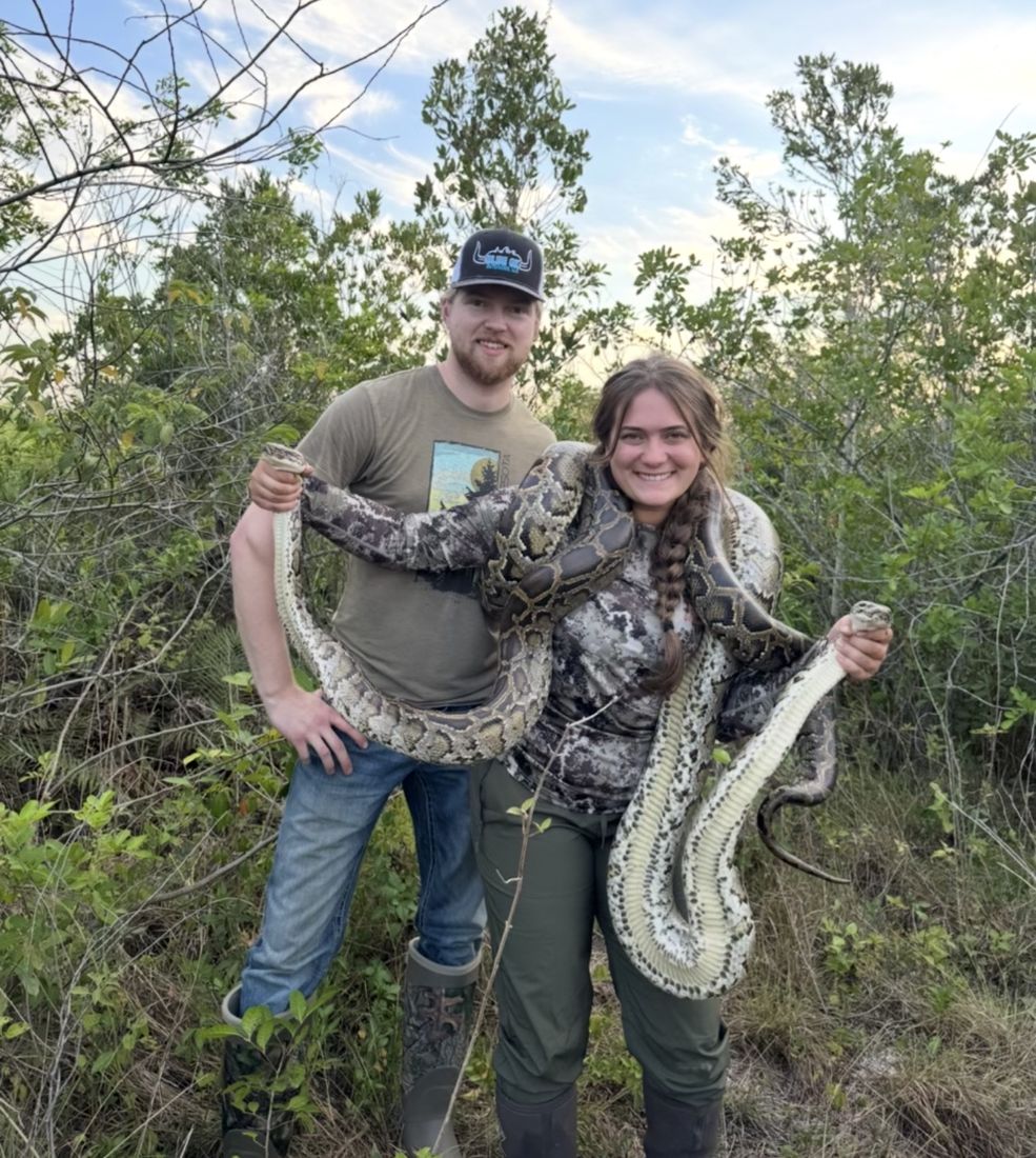 Two Allgood's Adventures hunters holding a large Burmese python in South Florida brush